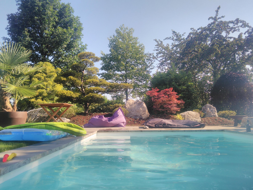 Diseño de piscina de estilo zen pequeña rectangular en patio lateral con paisajismo de piscina y adoquines de piedra natural
