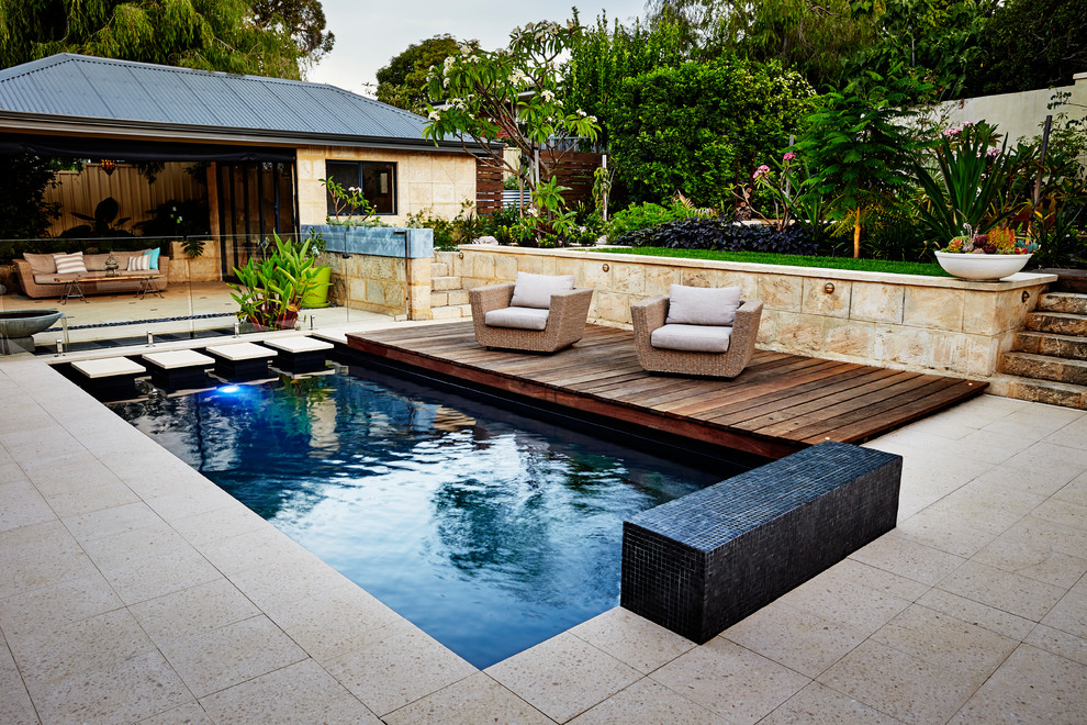 Modelo de piscina tropical rectangular en patio con suelo de baldosas