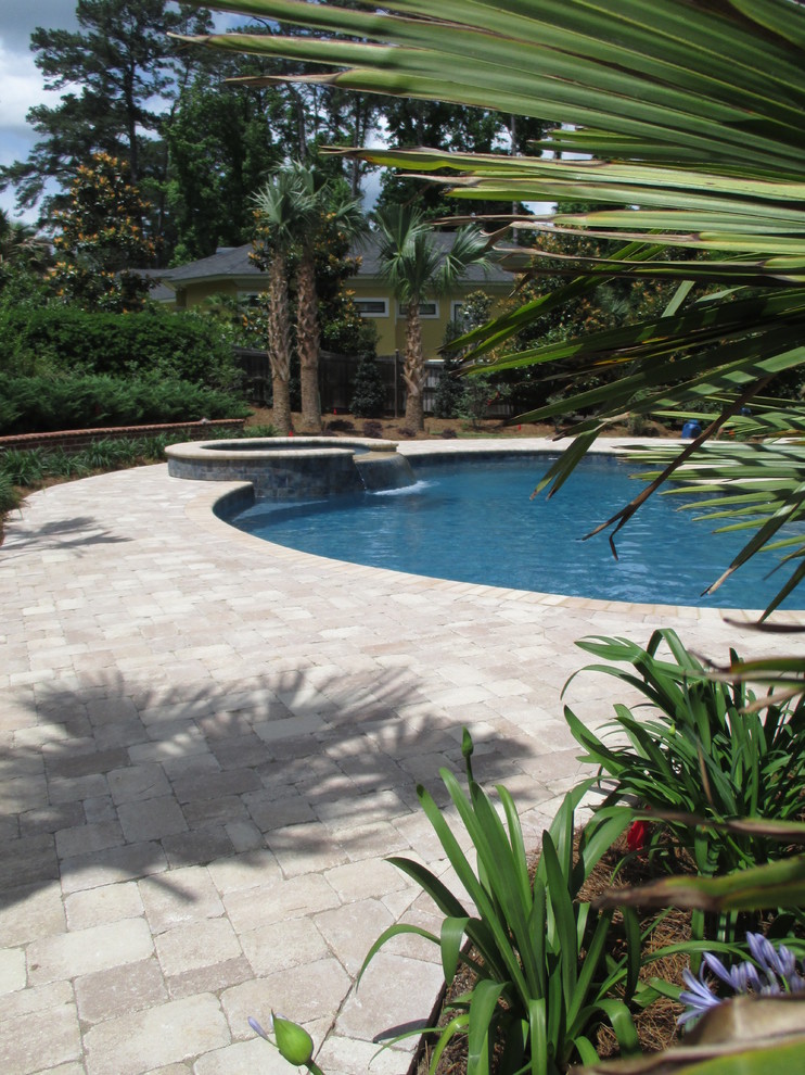 Пример оригинального дизайна: бассейн произвольной формы на заднем дворе в классическом стиле с покрытием из каменной брусчатки и джакузи