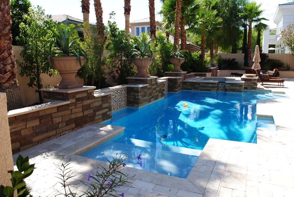 This is an example of a medium sized mediterranean back rectangular natural swimming pool in Las Vegas with a water feature and natural stone paving.