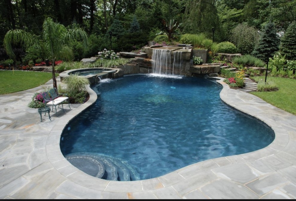 Modelo de piscinas y jacuzzis alargados actuales grandes a medida en patio trasero con suelo de hormigón estampado