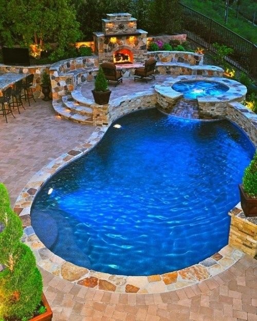 Ispirazione per una grande piscina naturale design a "C" dietro casa con una vasca idromassaggio e pavimentazioni in pietra naturale
