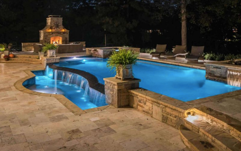 Ispirazione per una grande piscina naturale tropicale personalizzata dietro casa con pavimentazioni in pietra naturale e una vasca idromassaggio