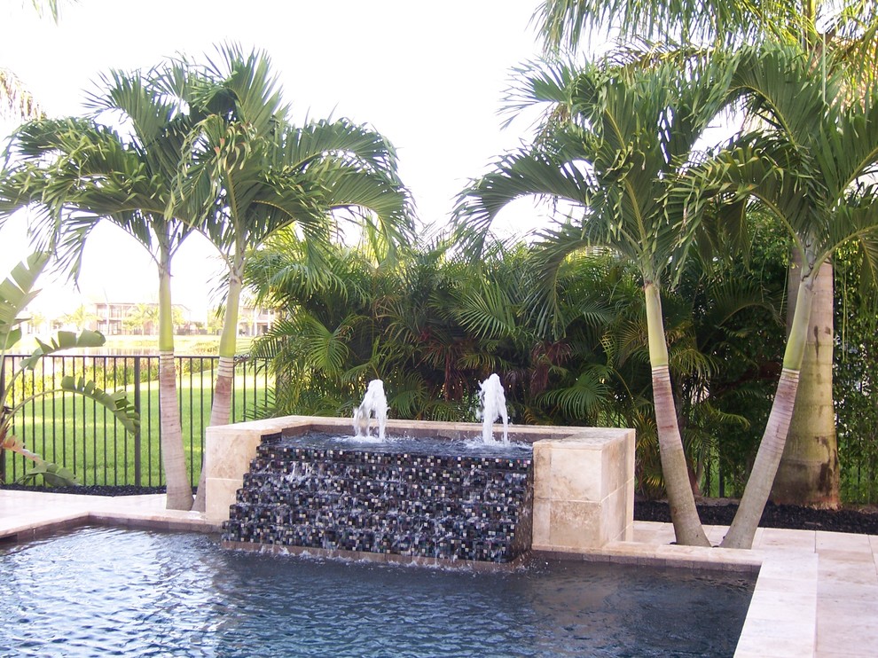 Esempio di una grande piscina monocorsia minimal rettangolare dietro casa con fontane e pavimentazioni in cemento