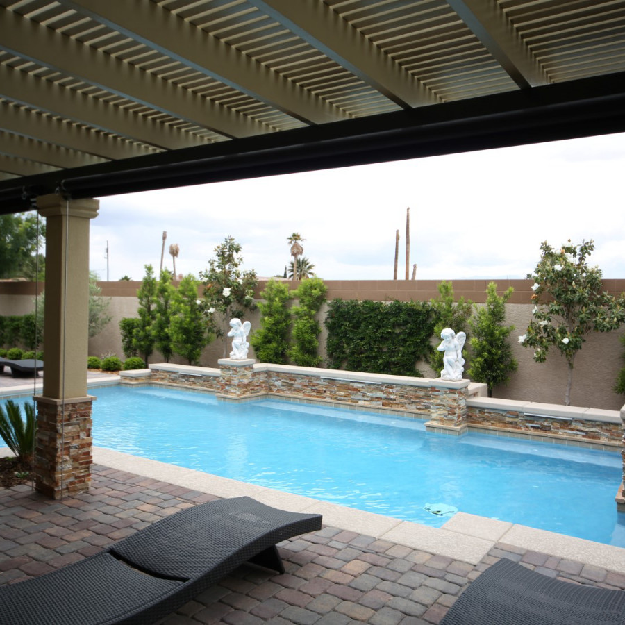 Ejemplo de piscina tradicional de tamaño medio rectangular en patio trasero con adoquines de ladrillo