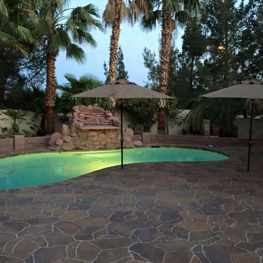Modelo de piscina con fuente tradicional de tamaño medio tipo riñón en patio trasero con adoquines de piedra natural