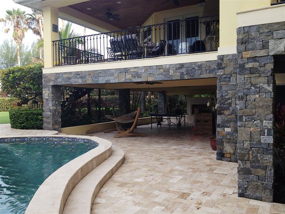 Idee per una grande piscina naturale tropicale a "C" dietro casa con fontane e piastrelle