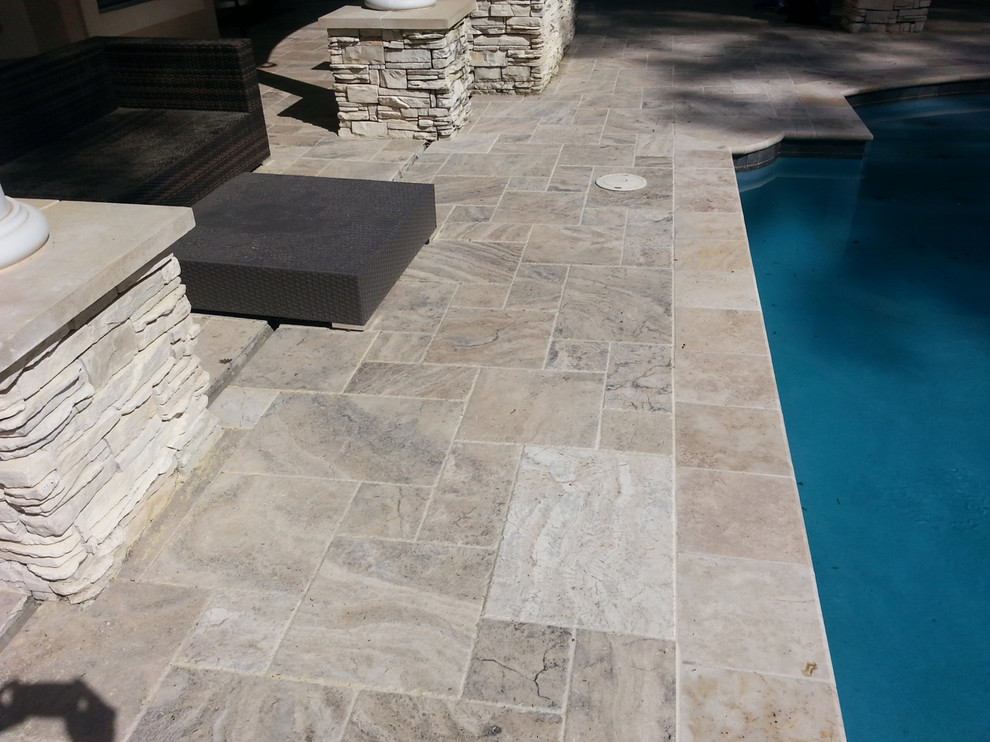 Large classic back rectangular lengths swimming pool in Dallas with a water feature and natural stone paving.