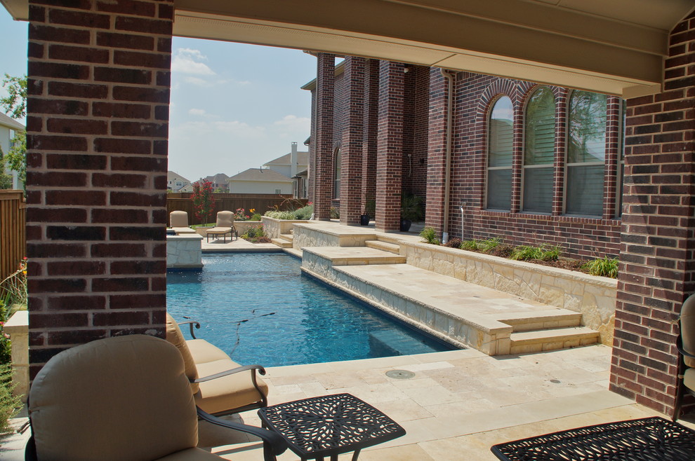 Diseño de piscina con fuente alargada clásica grande rectangular en patio trasero con adoquines de piedra natural