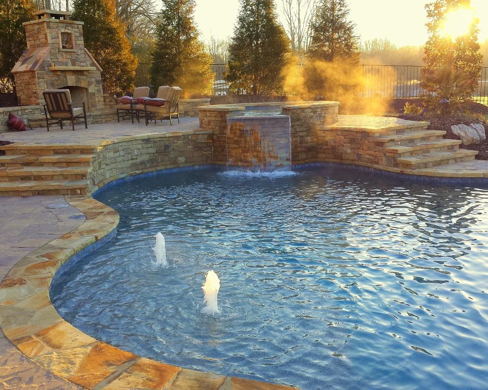Idée de décoration pour une grande piscine naturelle et arrière chalet sur mesure avec des pavés en pierre naturelle.
