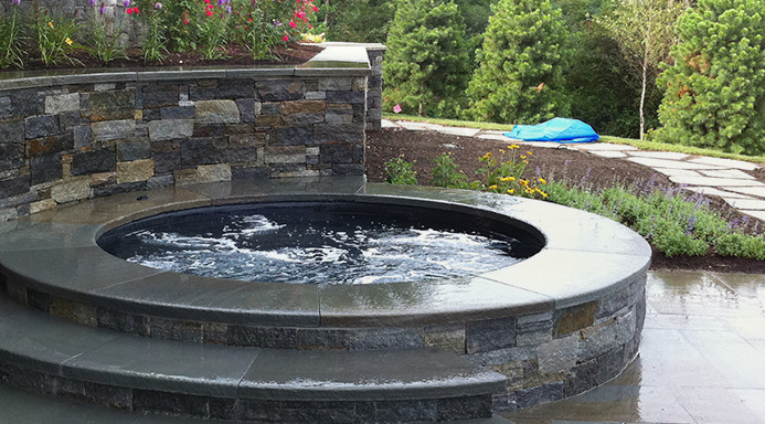 Inspiration pour une grande piscine arrière et naturelle minimaliste ronde avec un bain bouillonnant et des pavés en pierre naturelle.