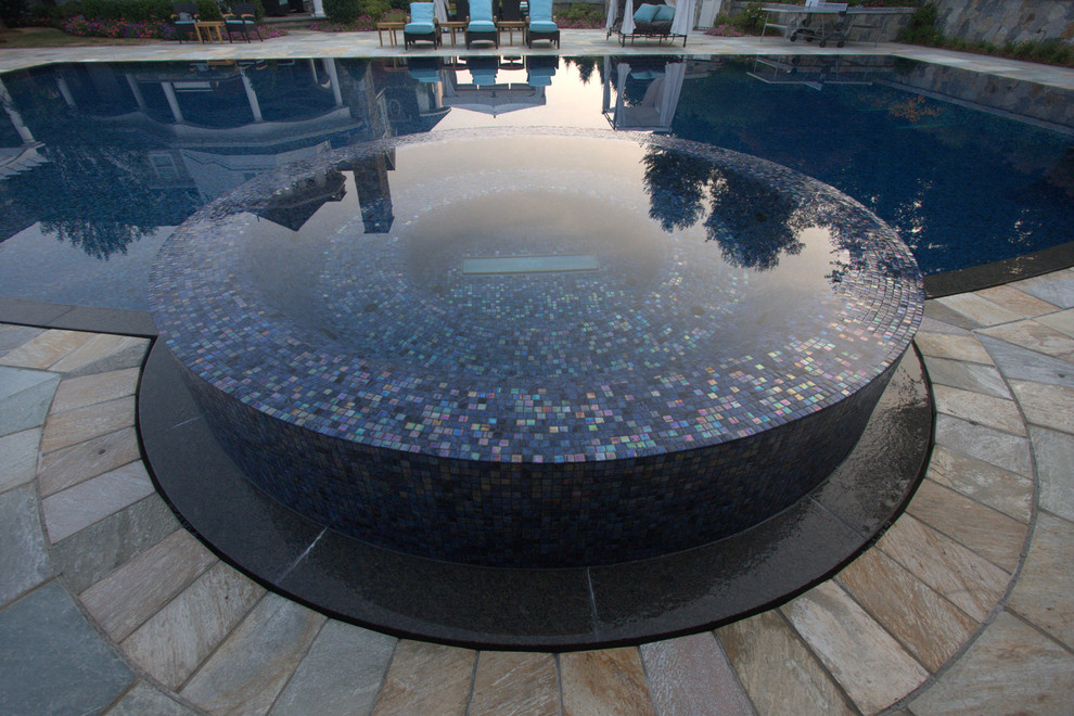 Diseño de piscinas y jacuzzis infinitos actuales grandes rectangulares en patio trasero con suelo de hormigón estampado