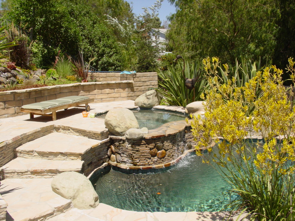 Design ideas for a large mediterranean back custom shaped natural hot tub in Los Angeles with natural stone paving.