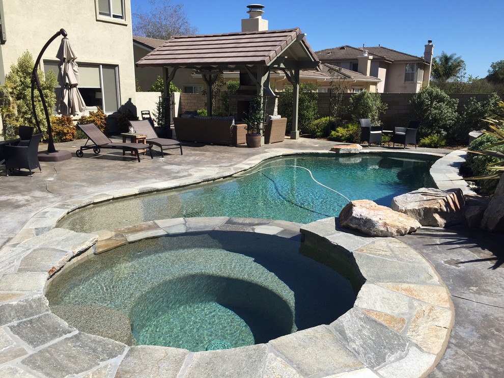 Esempio di una grande piscina naturale mediterranea personalizzata dietro casa con una vasca idromassaggio e pavimentazioni in pietra naturale