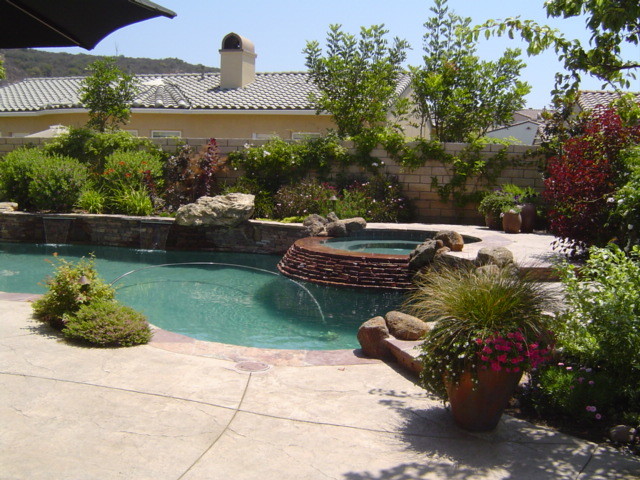 Свежая идея для дизайна: большой естественный бассейн произвольной формы на заднем дворе в средиземноморском стиле с джакузи и покрытием из каменной брусчатки - отличное фото интерьера