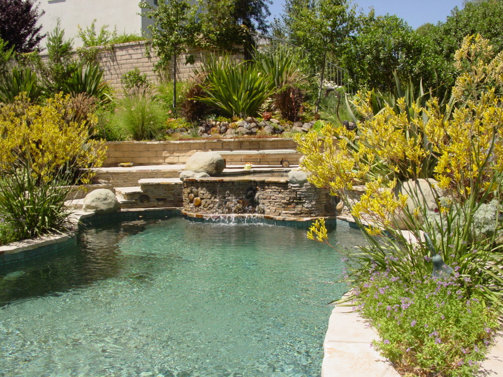 Cette photo montre une grande piscine naturelle et arrière méditerranéenne sur mesure avec un bain bouillonnant et des pavés en pierre naturelle.