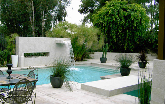 Exempel på en mellanstor modern rektangulär pool på baksidan av huset, med en fontän och naturstensplattor