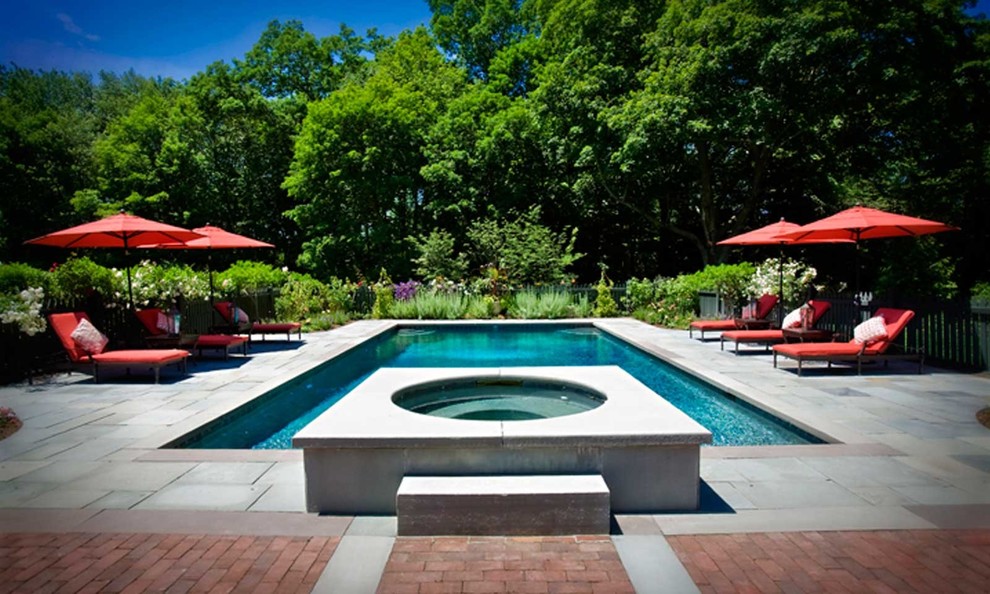 Esempio di una grande piscina monocorsia chic rettangolare dietro casa con una vasca idromassaggio e pavimentazioni in cemento