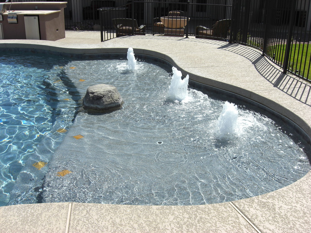 На фото: большой спортивный бассейн произвольной формы на заднем дворе в классическом стиле с фонтаном и покрытием из бетонных плит