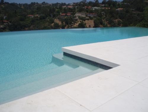 Imagen de piscina infinita minimalista en forma de L en patio trasero con losas de hormigón