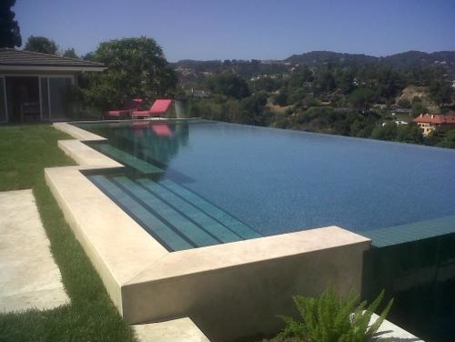 Idee per una grande piscina a sfioro infinito moderna personalizzata dietro casa con fontane e piastrelle