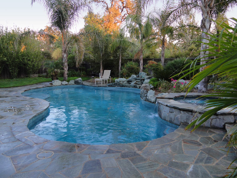 Ispirazione per una grande piscina naturale tropicale personalizzata dietro casa con una vasca idromassaggio e pavimentazioni in pietra naturale