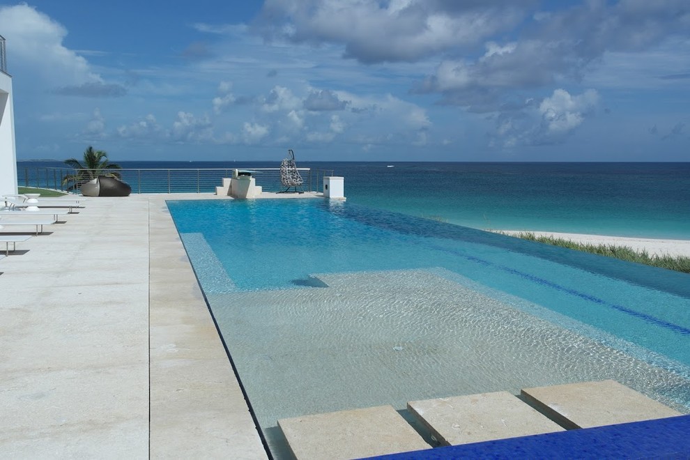 Imagen de piscina infinita exótica de tamaño medio a medida en patio trasero con losas de hormigón