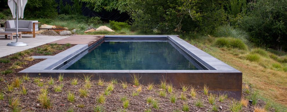 Foto de piscina con fuente elevada moderna de tamaño medio rectangular en patio delantero con entablado