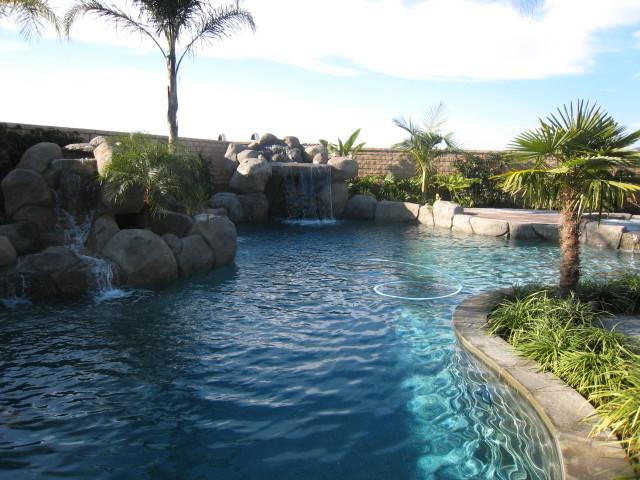 Ejemplo de piscina con fuente natural moderna de tamaño medio a medida en patio trasero con granito descompuesto
