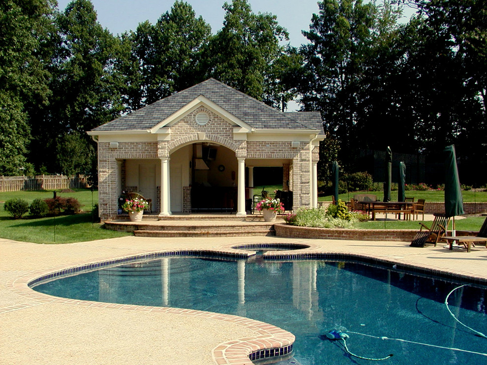 Foto di una grande piscina naturale tradizionale personalizzata dietro casa con pavimentazioni in mattoni e una vasca idromassaggio