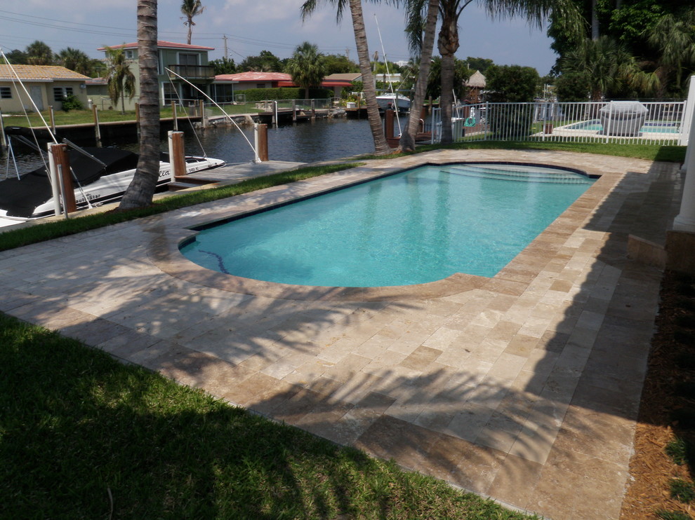 Imagen de piscina actual de tamaño medio rectangular en patio trasero con adoquines de piedra natural