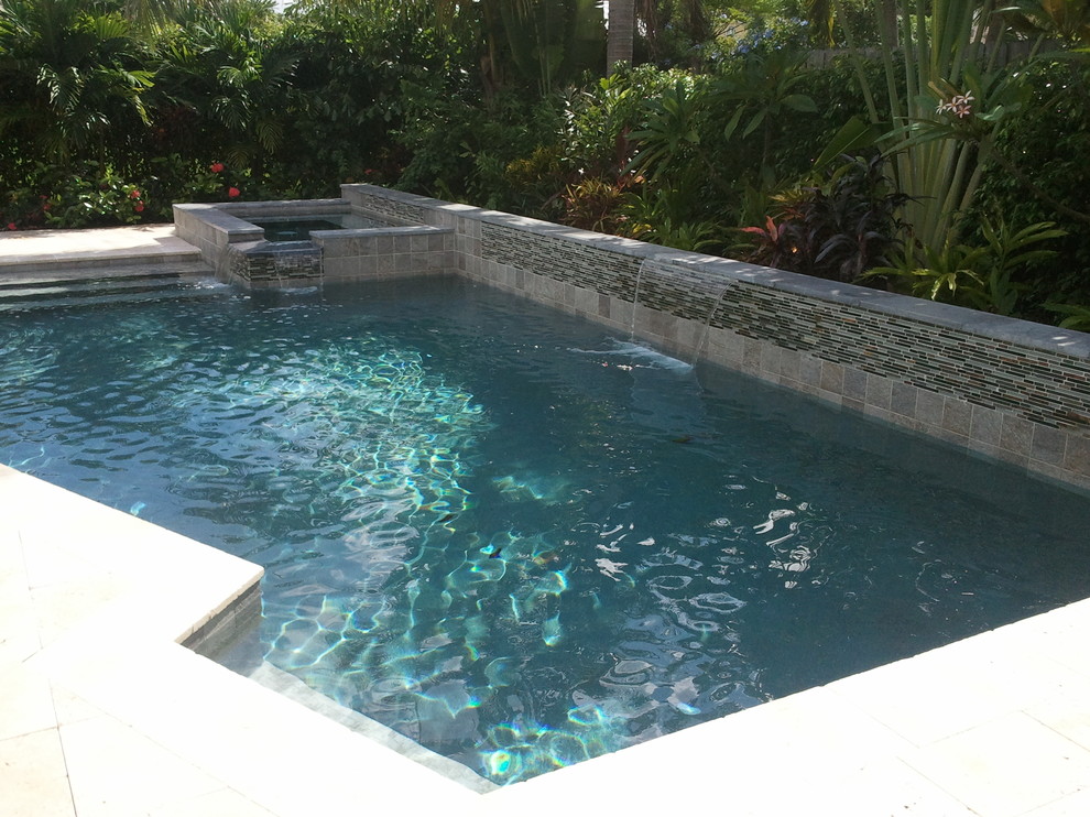 Ispirazione per una piccola piscina minimalista personalizzata dietro casa con una vasca idromassaggio e pavimentazioni in pietra naturale