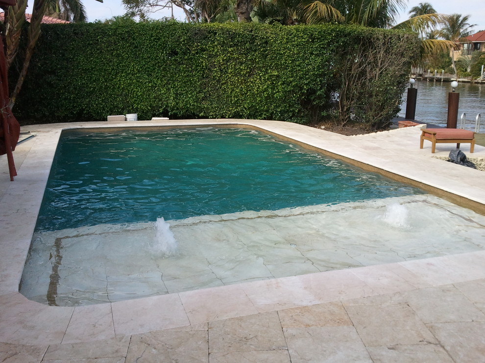 Kleiner Klassischer Pool hinter dem Haus in rechteckiger Form mit Wasserspiel und Natursteinplatten in Miami