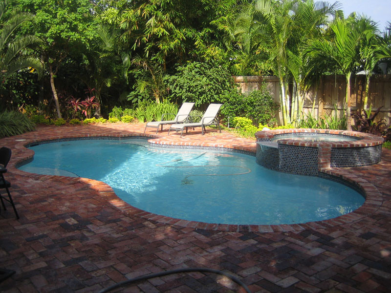 Mid-sized trendy backyard brick and custom-shaped hot tub photo in Miami