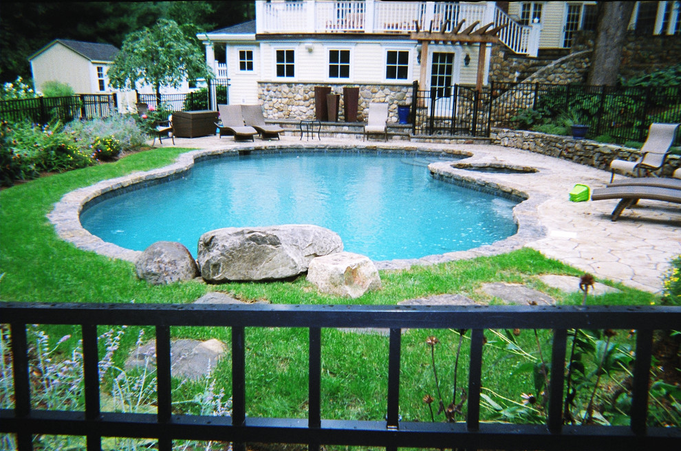 Стильный дизайн: бассейн в форме фасоли на заднем дворе с покрытием из каменной брусчатки и джакузи - последний тренд