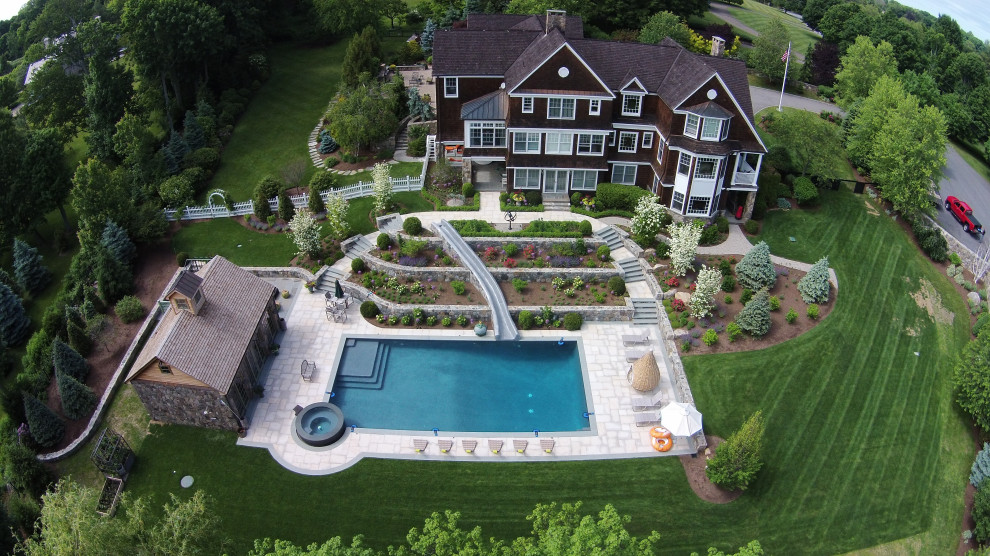 На фото: большой прямоугольный бассейн на заднем дворе в классическом стиле с водной горкой