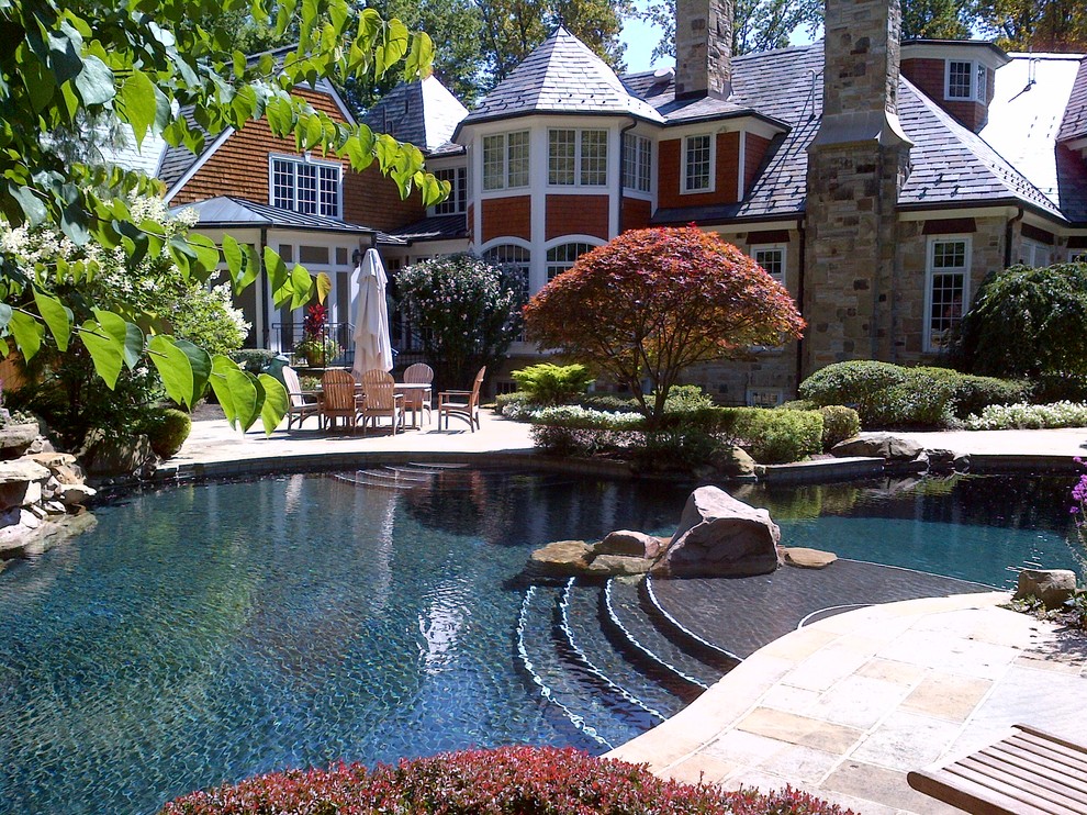 Foto på en mellanstor funkis pool på baksidan av huset, med en fontän och naturstensplattor