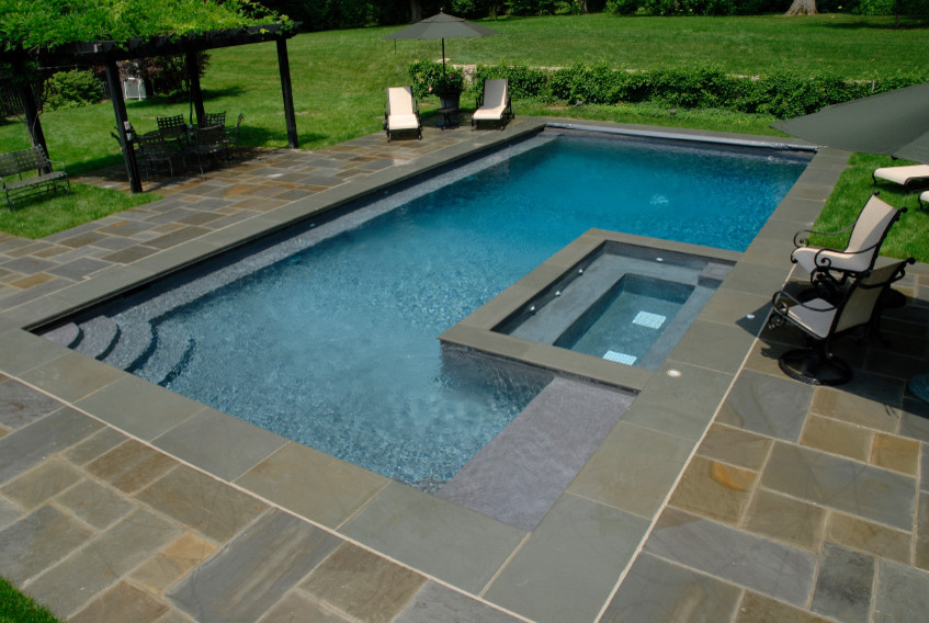 Cette image montre un couloir de nage arrière traditionnel de taille moyenne et rectangle avec un bain bouillonnant et des pavés en pierre naturelle.