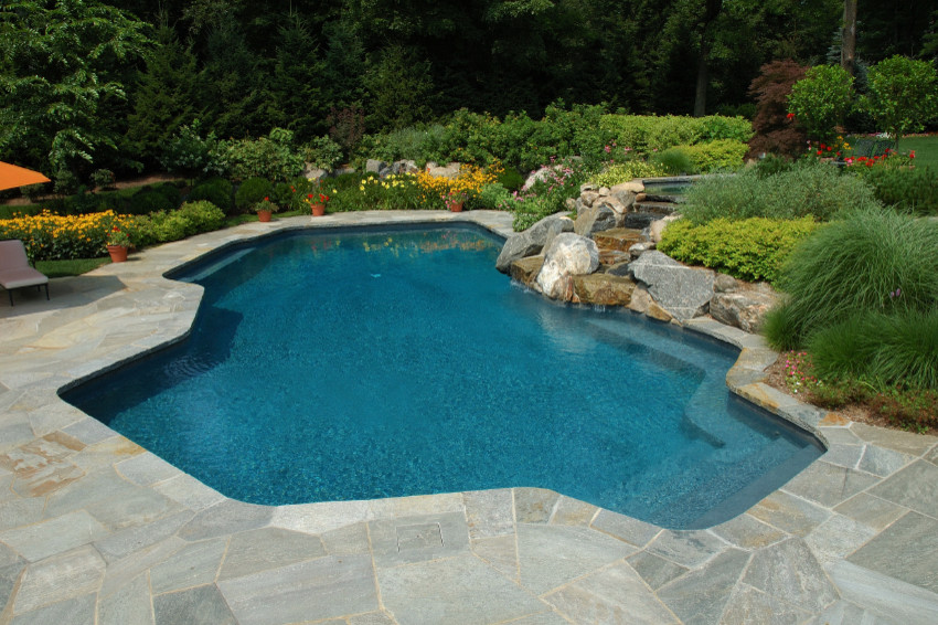 Foto de piscinas y jacuzzis clásicos de tamaño medio a medida en patio trasero con adoquines de piedra natural