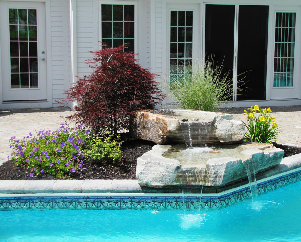 Immagine di una piscina monocorsia classica personalizzata di medie dimensioni e dietro casa con fontane e pavimentazioni in pietra naturale