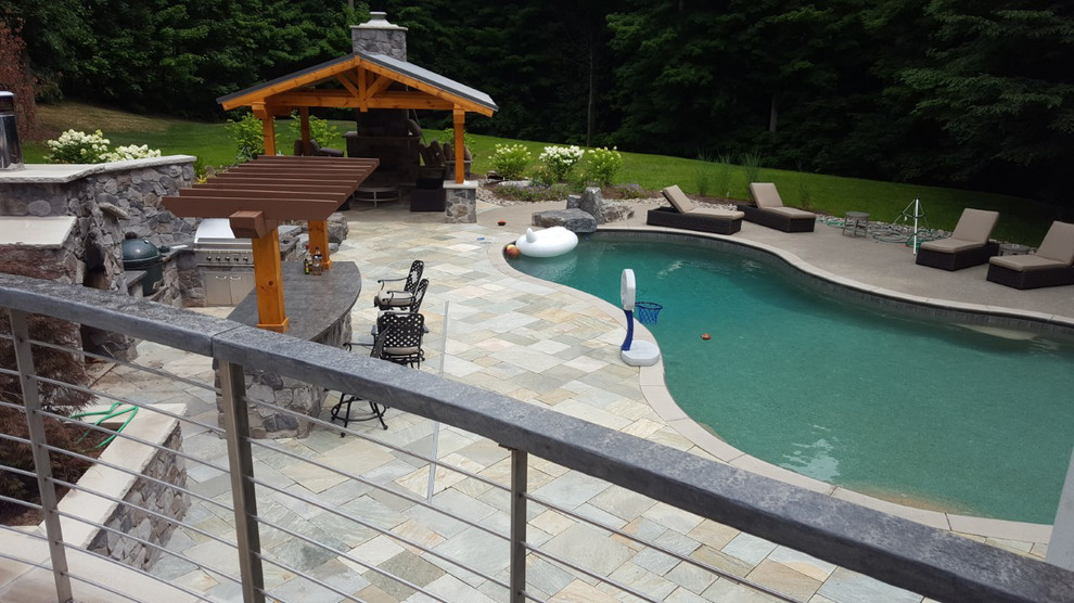 Example of a huge classic backyard stone and custom-shaped lap pool fountain design in New York