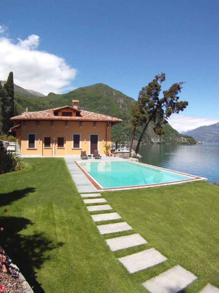 Idee per un'ampia piscina naturale chic rettangolare dietro casa con pavimentazioni in pietra naturale
