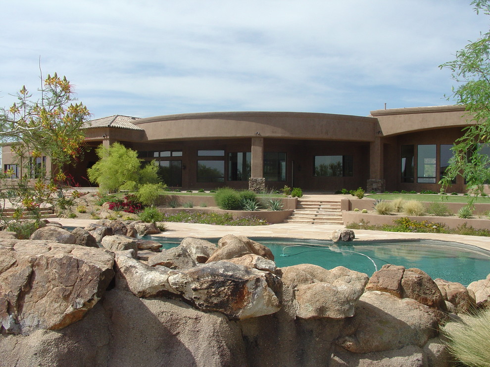 Geräumiger Mediterraner Schwimmteich hinter dem Haus in individueller Form mit Wasserspiel und Natursteinplatten in Phoenix