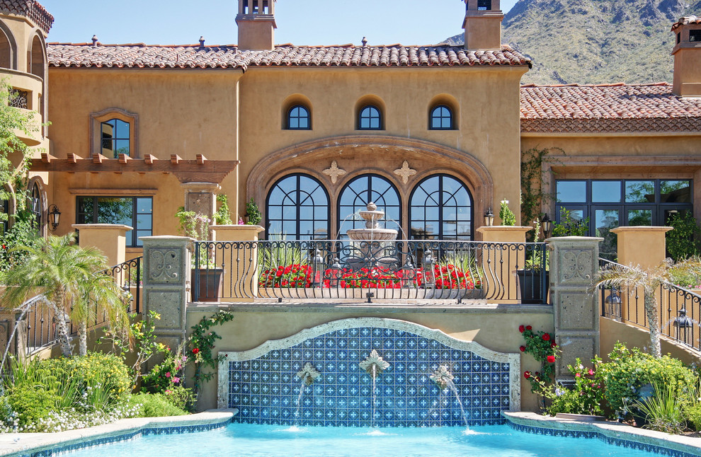 Immagine di un'ampia piscina naturale mediterranea personalizzata dietro casa con fontane e pavimentazioni in pietra naturale