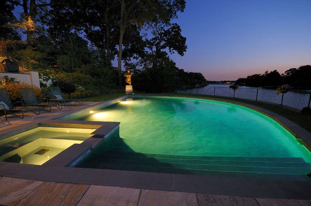 Ejemplo de piscina actual de tamaño medio a medida en patio trasero con adoquines de piedra natural