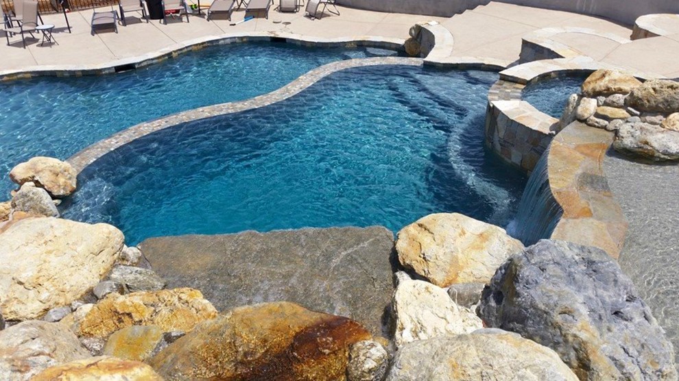Ispirazione per una grande piscina naturale tradizionale personalizzata dietro casa con un acquascivolo e lastre di cemento
