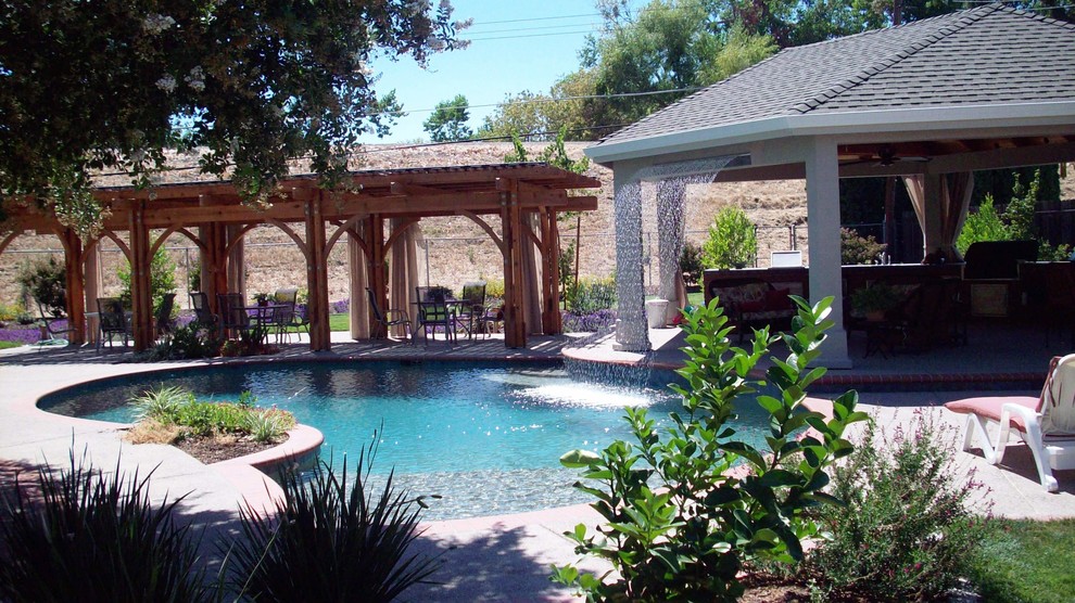 На фото: бассейн среднего размера, произвольной формы на заднем дворе с джакузи и покрытием из декоративного бетона