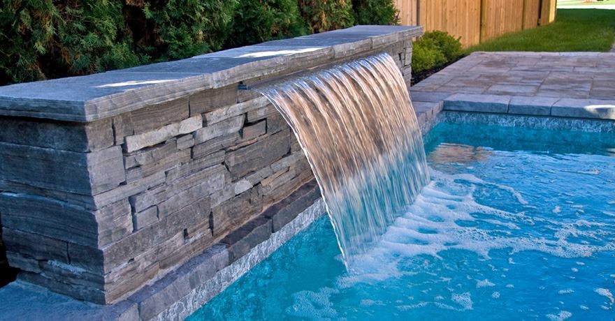 На фото: большой естественный бассейн произвольной формы на заднем дворе в классическом стиле с покрытием из каменной брусчатки и фонтаном