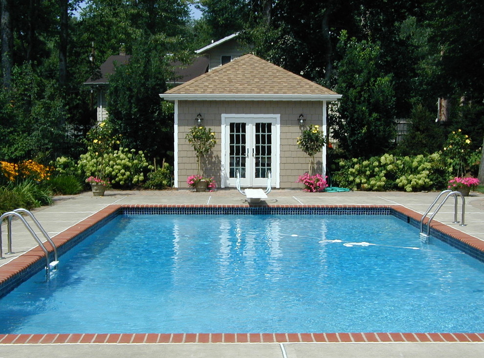 Идея дизайна: прямоугольный бассейн среднего размера на заднем дворе в классическом стиле с домиком у бассейна и покрытием из бетонных плит