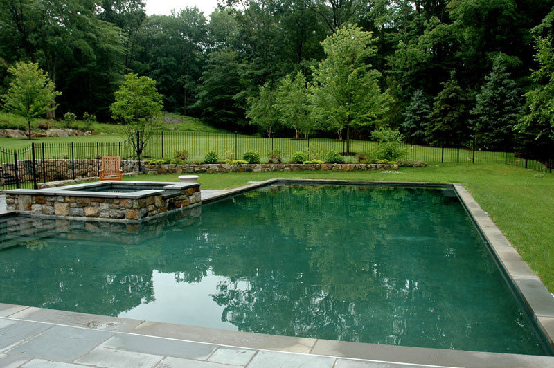 Example of a large classic backyard stamped concrete and l-shaped lap hot tub design in New York